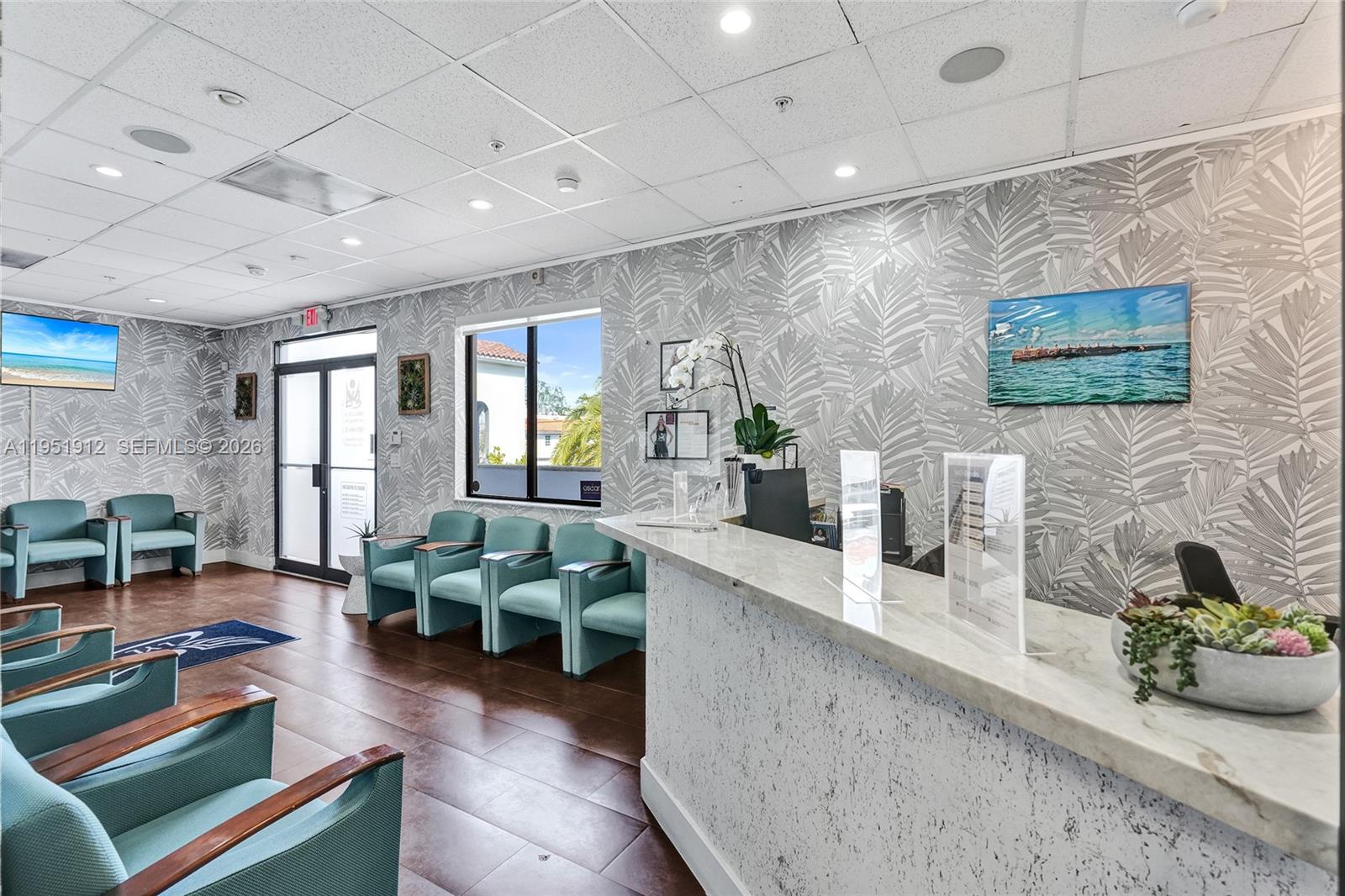 A reception area features a marble-topped desk, teal armchairs, and palm-patterned wallpaper — 7374 SW 93rd Ave # B, Miami FL 33173, MIAMI, FL