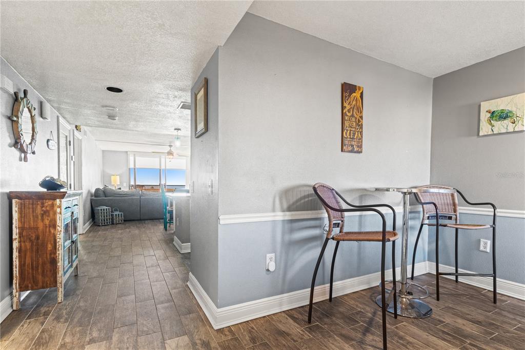 A dining area with a bistro table and chairs leads into a living room — 6035 SEA RANCH DRIVE UNIT 415, HUDSON, FL