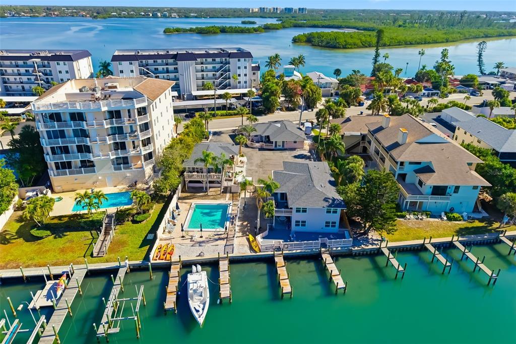 An aerial view shows waterfront residential buildings, swimming pools, and private boat docks — 9022 MIDNIGHT PASS ROAD, SARASOTA, FL