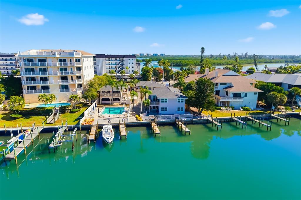 An aerial view shows waterfront homes and a multi-story apartment building with a swimming pool — 9022 MIDNIGHT PASS ROAD, SARASOTA, FL