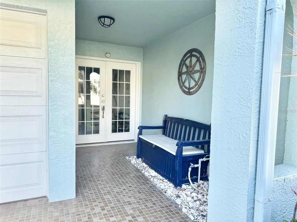 A covered entryway features a tiled floor, a blue storage bench, and white double doors — 603 GARLAND CIRCLE, INDIAN ROCKS BEACH, FL