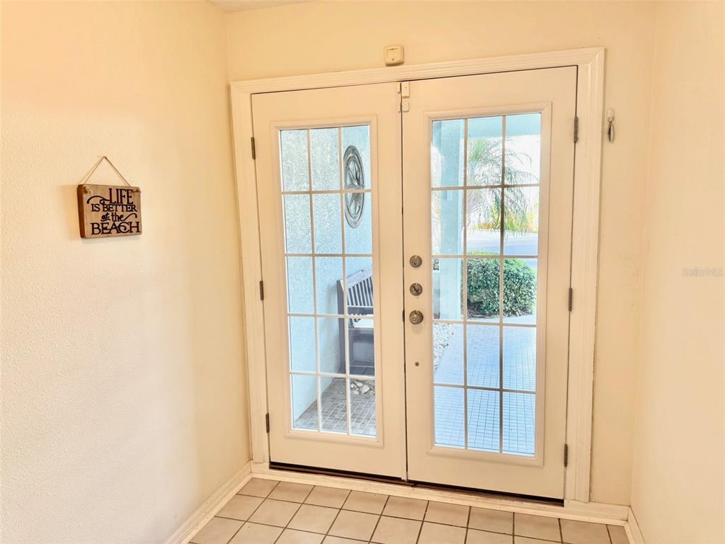 A tiled entryway features white double glass doors and a beach-themed wall sign — 603 GARLAND CIRCLE, INDIAN ROCKS BEACH, FL