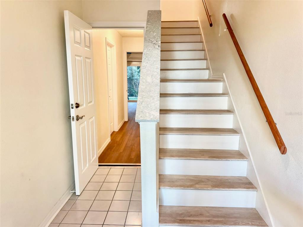A staircase with light wood treads and white risers sits beside a tiled entryway — 603 GARLAND CIRCLE, INDIAN ROCKS BEACH, FL