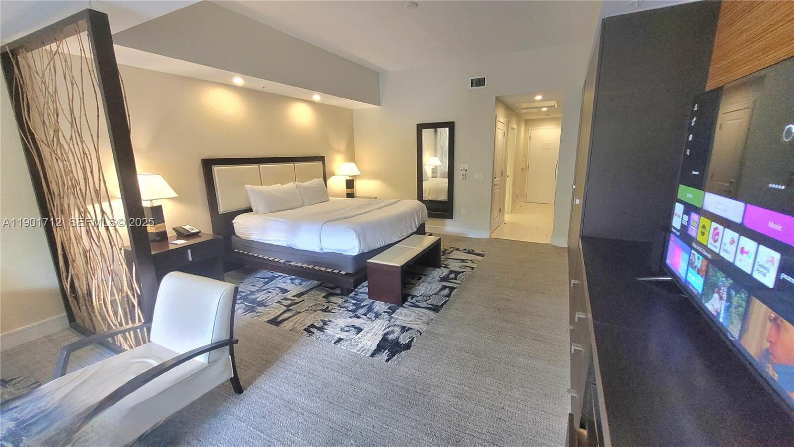 A hotel bedroom features a king bed, a television, and a decorative room divider — 5300 NW 87th Ave # 306, Doral FL 33178, DORAL, FL