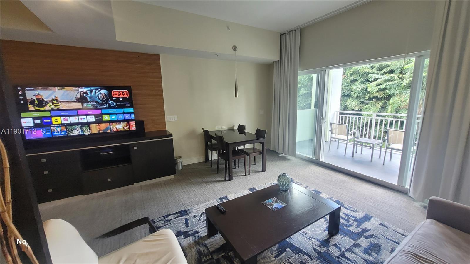 A living room features a television, dining set, coffee table, and a balcony with outdoor seating — 5300 NW 87th Ave # 306, Doral FL 33178, DORAL, FL