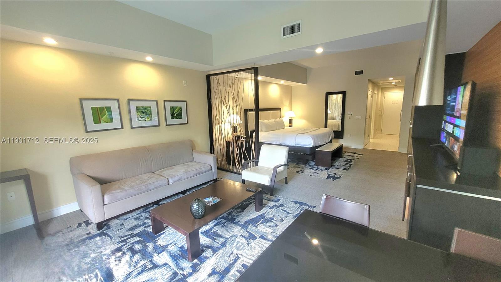 A hotel-style suite features a living area with a sofa, coffee table, and bedroom space — 5300 NW 87th Ave # 306, Doral FL 33178, DORAL, FL