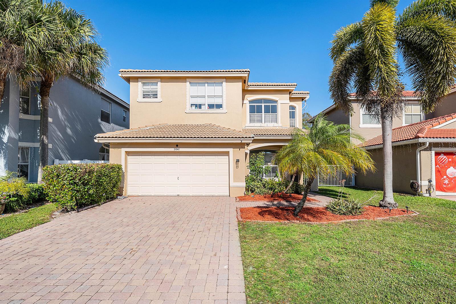 A two-story suburban house with a beige stucco exterior, tiled roof, and paved driveway — 5041 Massy Drive, Lake Worth FL 33463, LAKE WORTH, FL