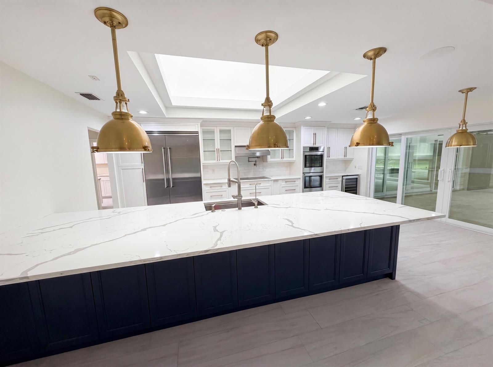 A modern kitchen features a large dark blue island with a white marble countertop — 296 Wychmere Terrace, Wellington FL 33414, WELLINGTON, FL