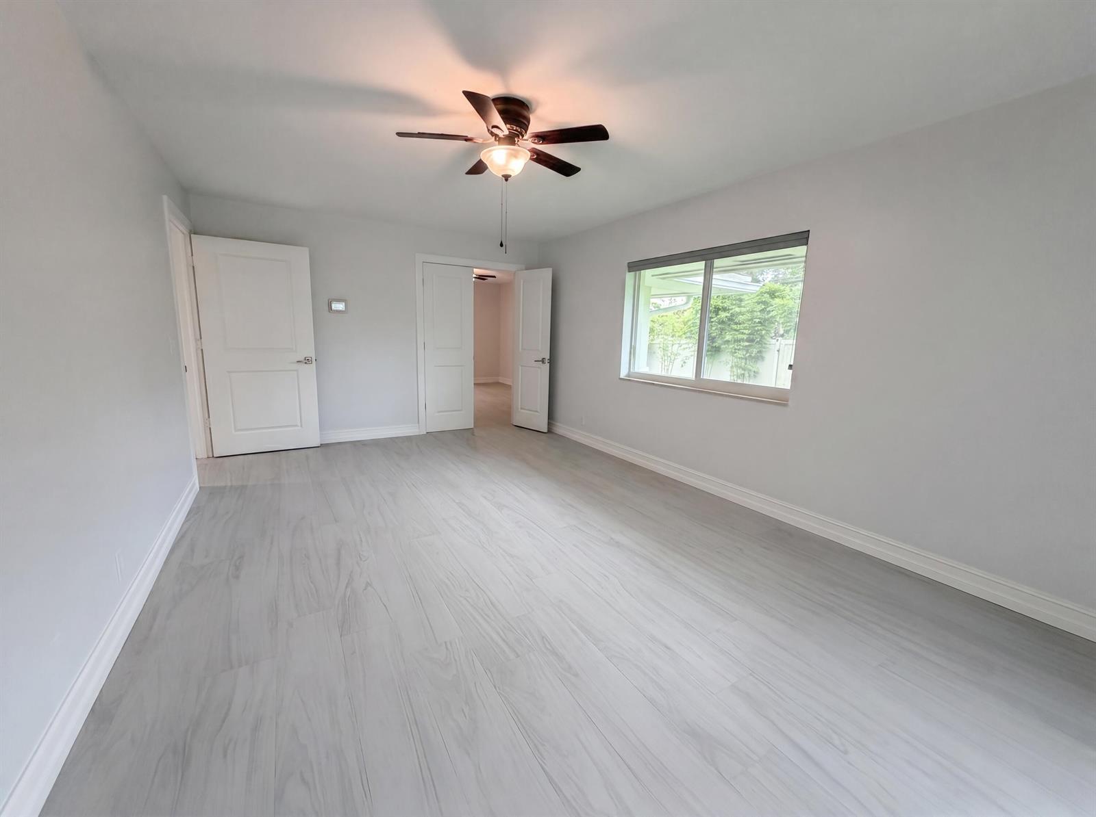 An empty bedroom features light gray walls, wood-look flooring, a ceiling fan, and two doorways — 296 Wychmere Terrace, Wellington FL 33414, WELLINGTON, FL