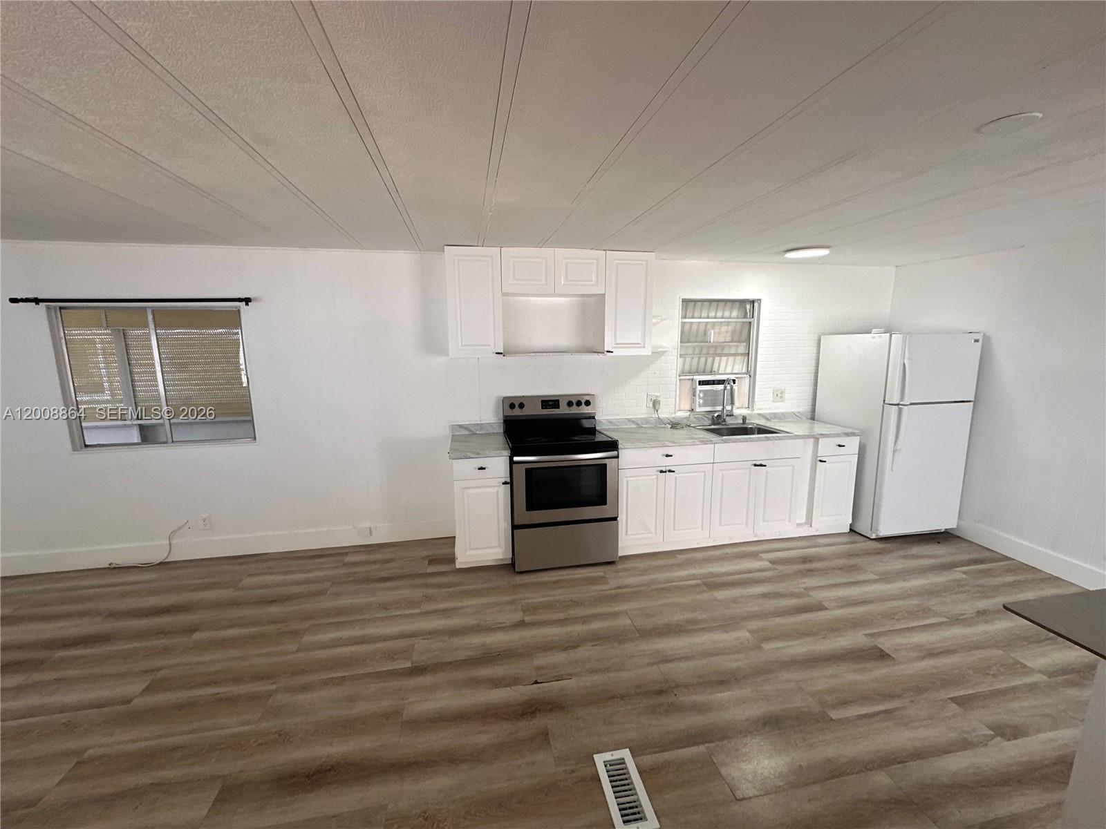 A kitchen features white cabinets, stainless steel appliances, and light wood-look flooring — 2957 SW 54th St # 0, Dania Beach FL 33312, DANIA BEACH, FL