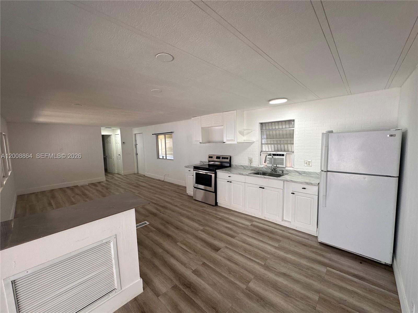 A kitchen with white cabinets, stainless steel appliances, and wood-look flooring — 2957 SW 54th St # 0, Dania Beach FL 33312, DANIA BEACH, FL