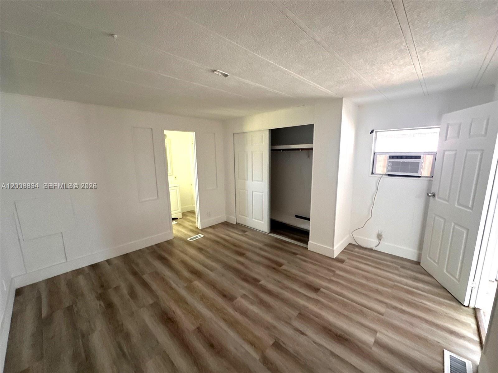 A bedroom features light wood-look flooring, white walls, a closet, and an attached bathroom — 2957 SW 54th St # 0, Dania Beach FL 33312, DANIA BEACH, FL