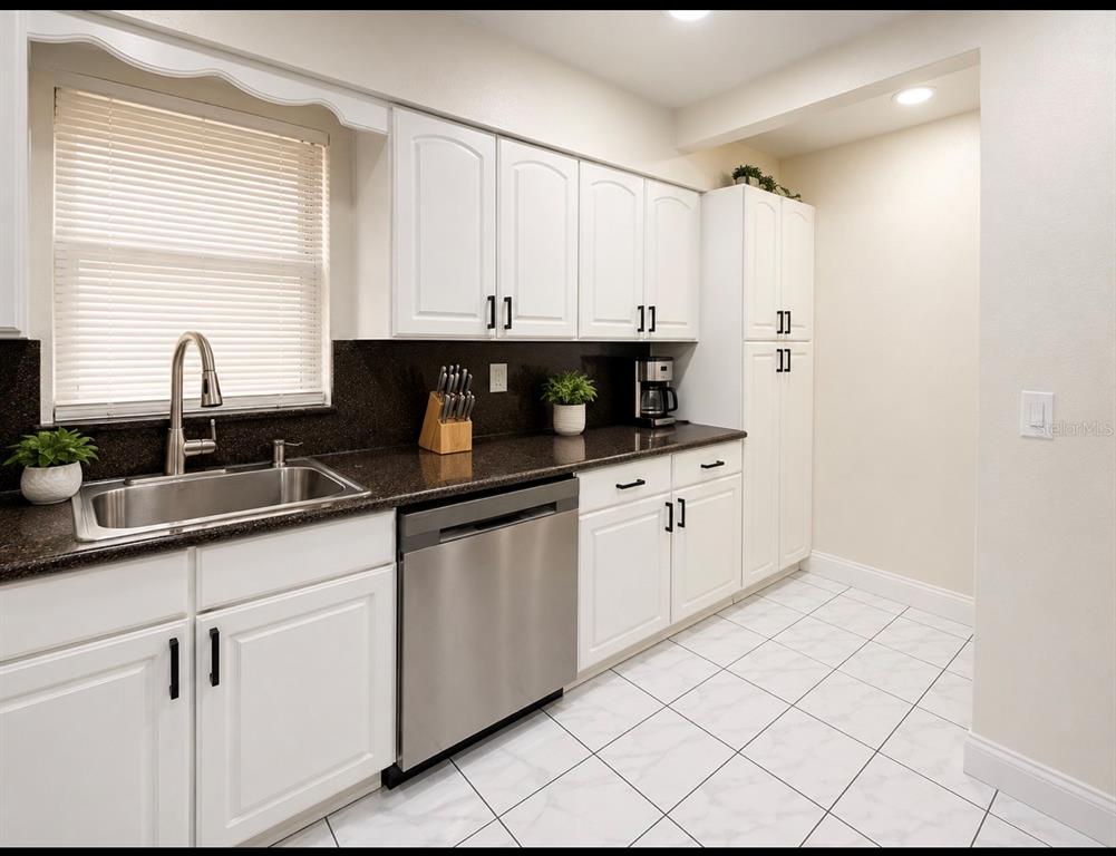 A kitchen with white cabinets, dark countertops, stainless steel appliances, and white tiled flooring — 1618 CRYSTALVIEW TRAIL, LAKELAND, FL