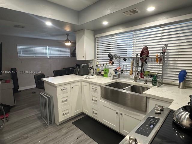 A kitchen features white cabinets, a farmhouse sink, and light countertops with grey flooring — 6757 Arbor Dr, Miramar FL 33023, MIRAMAR, FL