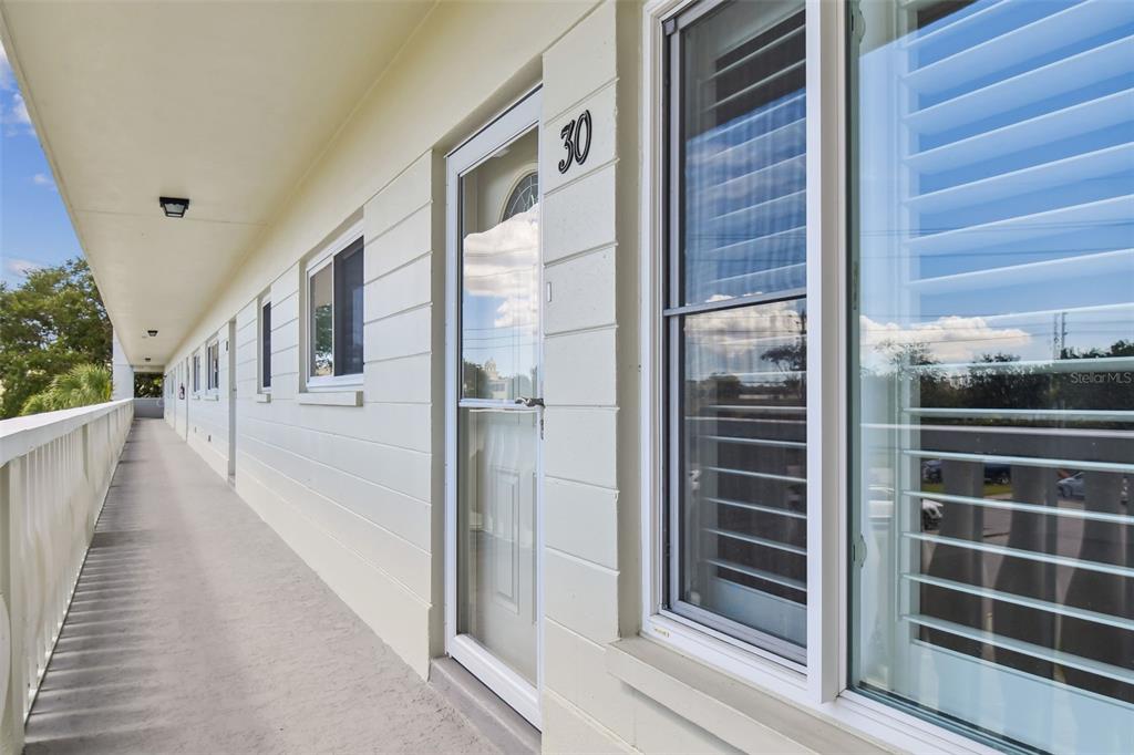 An exterior walkway with a white railing leads to a door marked with number 30 — 2292 COSTA RICAN DRIVE UNIT 30, CLEARWATER, FL