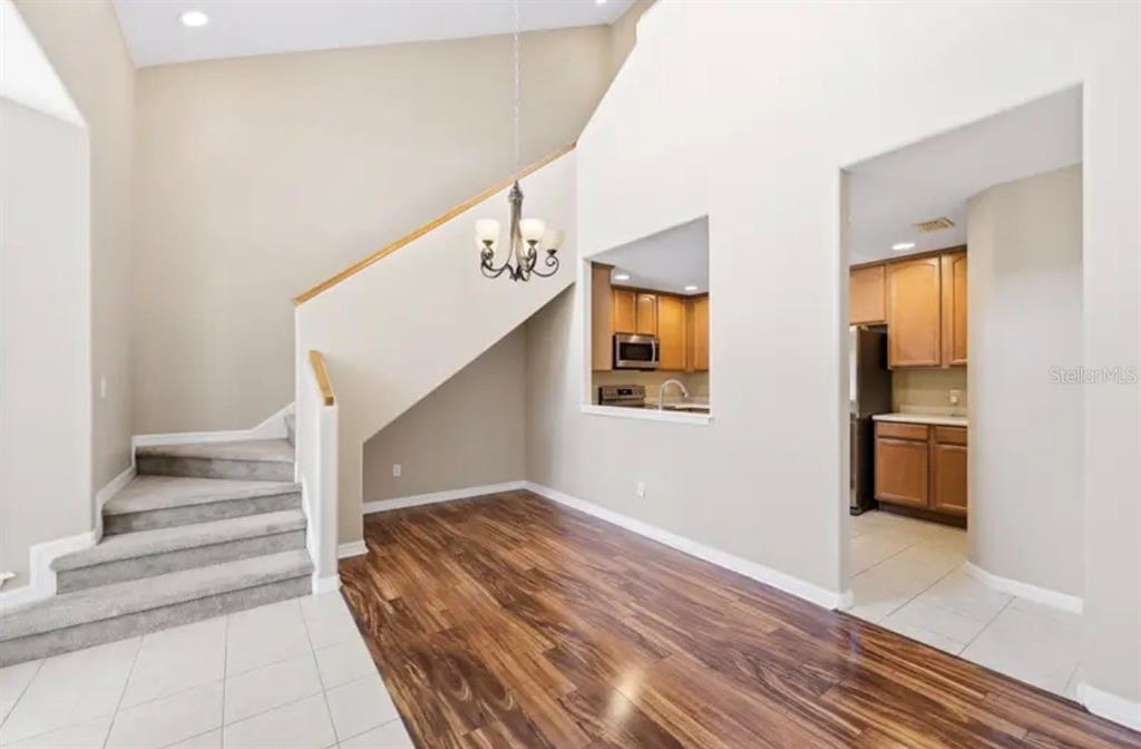 An entryway with tiled flooring leads into a living room featuring vaulted ceilings and wood floors — 316 NAUTICA MILE DRIVE, CLERMONT, FL