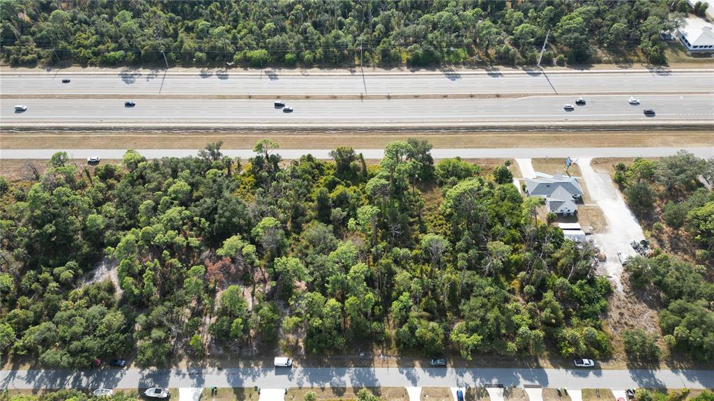 An aerial view shows a wooded lot situated between a highway and a residential street — 380 TAMIAMI TRAIL, PORT CHARLOTTE, FL