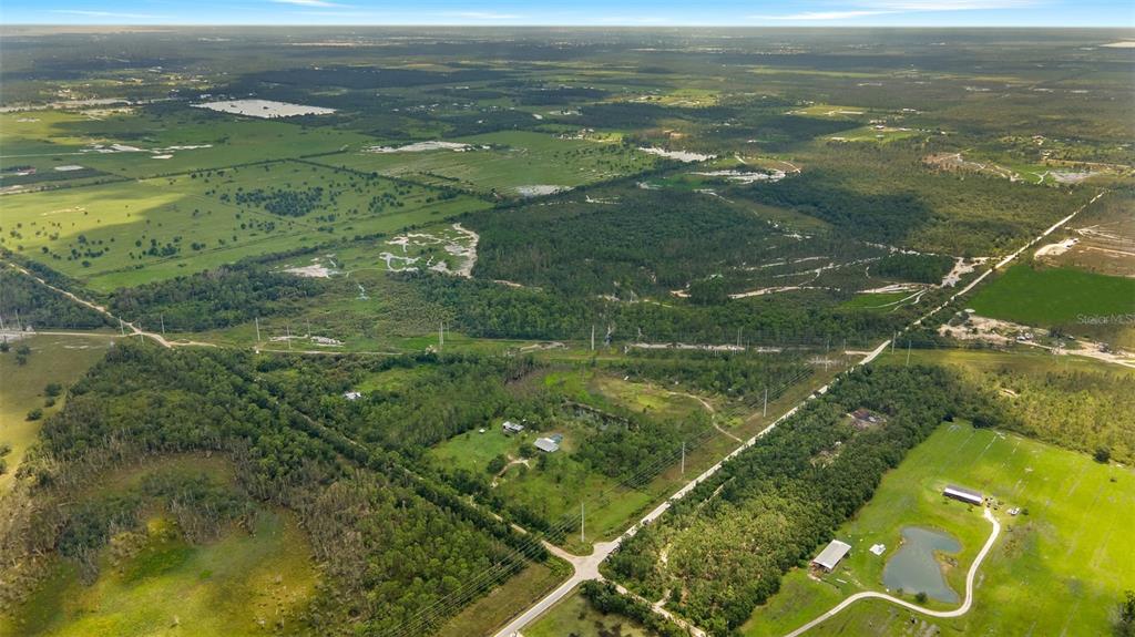 An aerial view shows a rural landscape with scattered houses, wooded areas, and open fields — 37381 COOK BROWN ROAD, FORT MYERS, FL