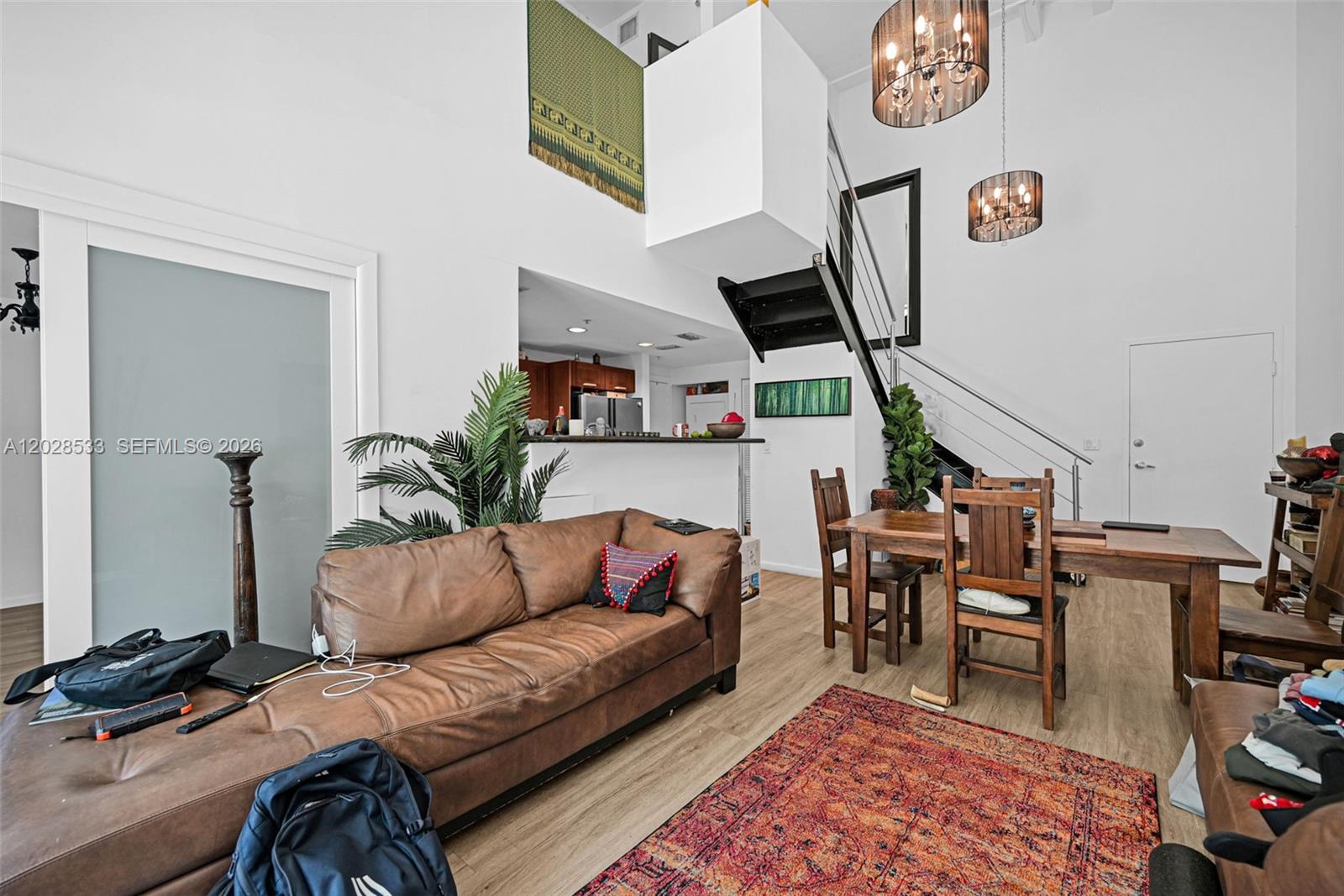 A living and dining area features a brown leather sofa, wooden table, and staircase — 7728 Collins Ave # 5, Miami Beach FL 33141, MIAMI BEACH, FL