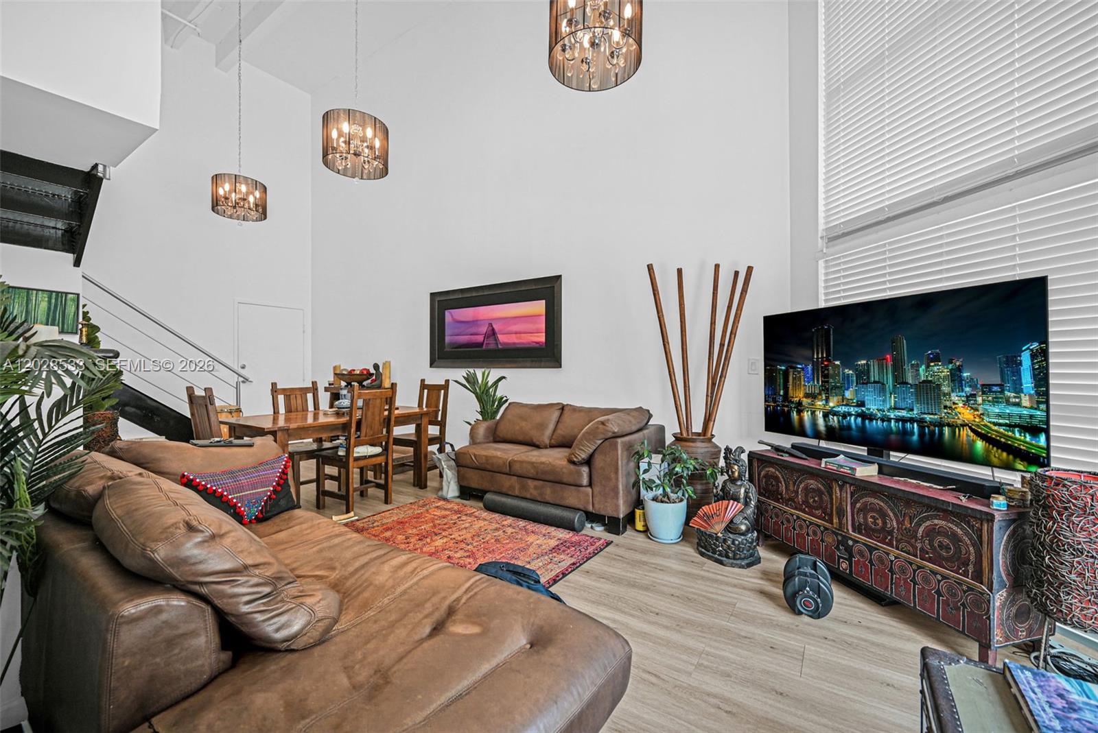 A living room with high ceilings, brown leather sofas, a dining area, and a television — 7728 Collins Ave # 5, Miami Beach FL 33141, MIAMI BEACH, FL
