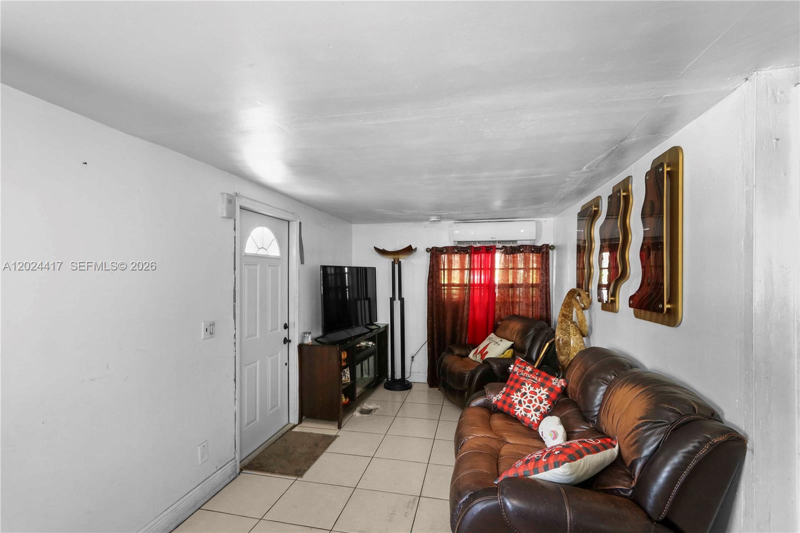 A living room features white walls, tile flooring, a brown leather sofa, and a television — 827 SW 128 AVE, Miami FL 33184, MIAMI, FL