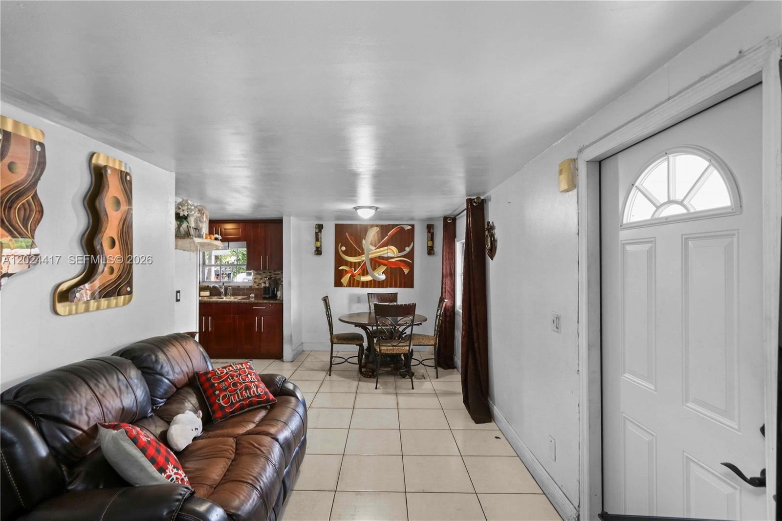 A living room with tile floors, a leather sofa, and a dining area — 827 SW 128 AVE, Miami FL 33184, MIAMI, FL