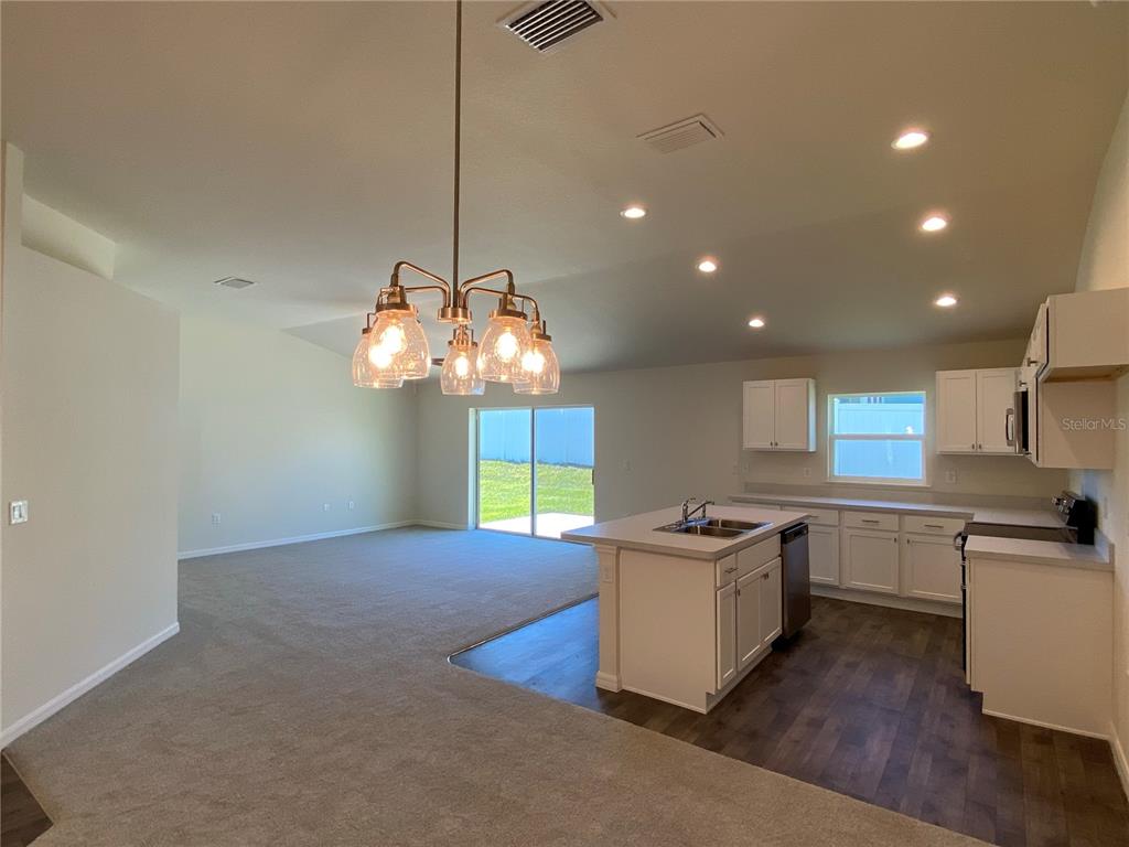 An open-concept kitchen and living area features white cabinetry, a center island, and carpeting — 8190 N WAKEFIELD DRIVE, CITRUS SPRINGS, FL