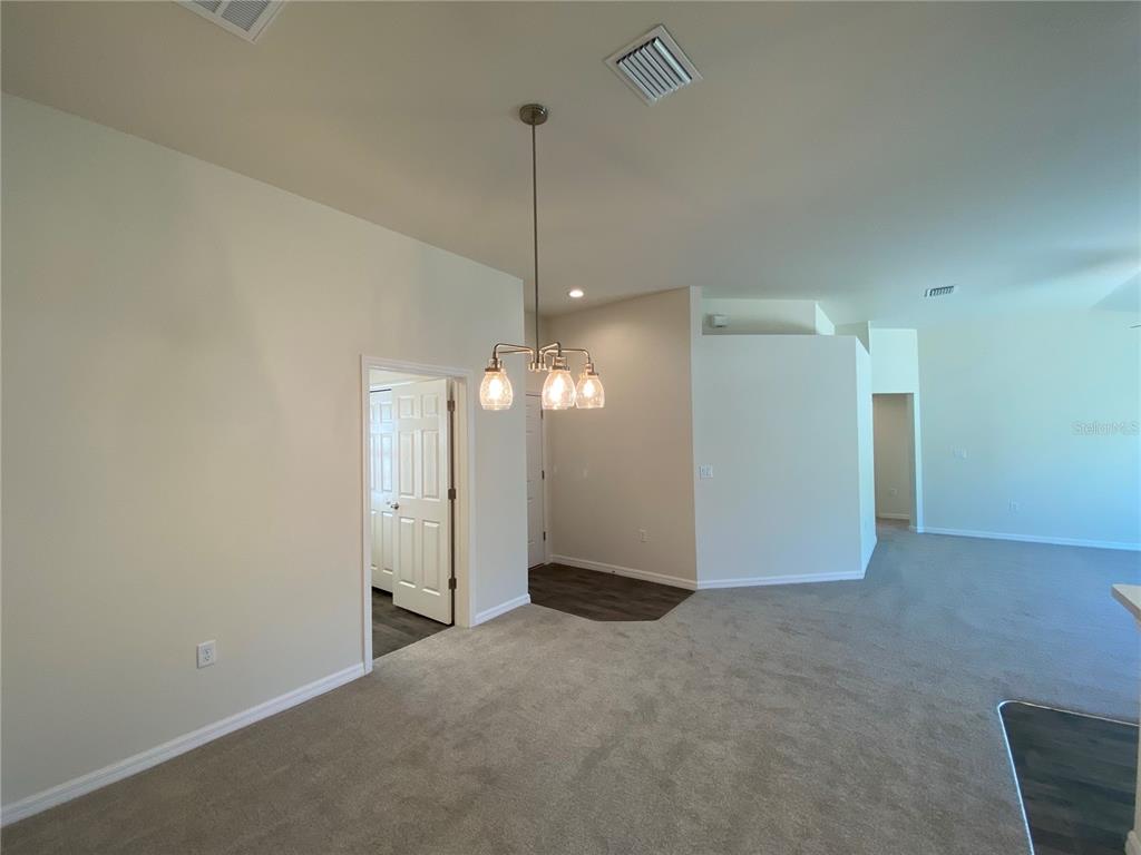 A dining area with a hanging light fixture, carpeted flooring, and an adjacent doorway — 8190 N WAKEFIELD DRIVE, CITRUS SPRINGS, FL