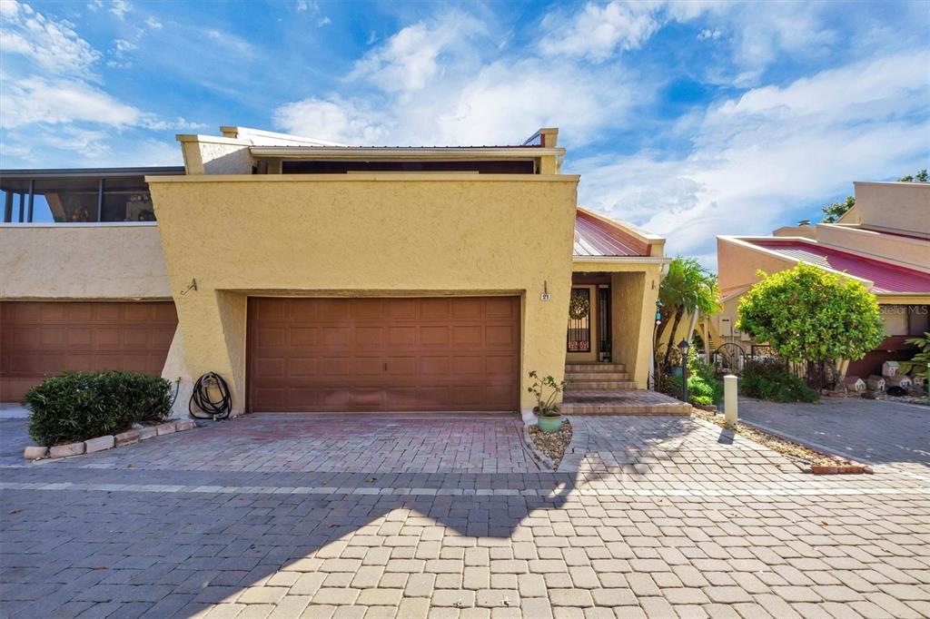 A yellow stucco house with a brown garage door and a paved driveway — 21 CASARENA COURT, WINTER HAVEN, FL