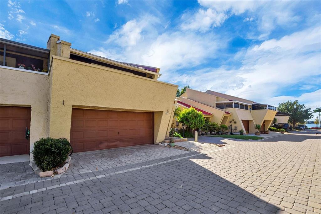 A view of a tan stucco townhouse exterior with a garage and paved driveway — 21 CASARENA COURT, WINTER HAVEN, FL