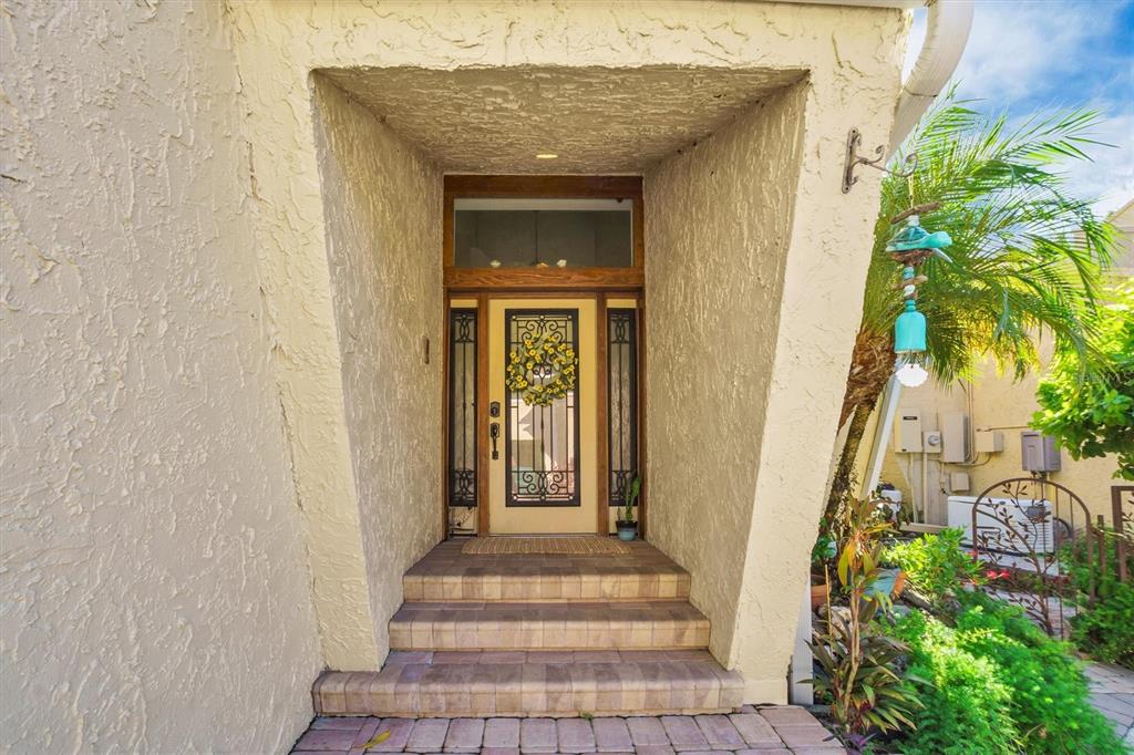 A front entrance with a decorative glass door, side lights, and steps leading to a porch — 21 CASARENA COURT, WINTER HAVEN, FL