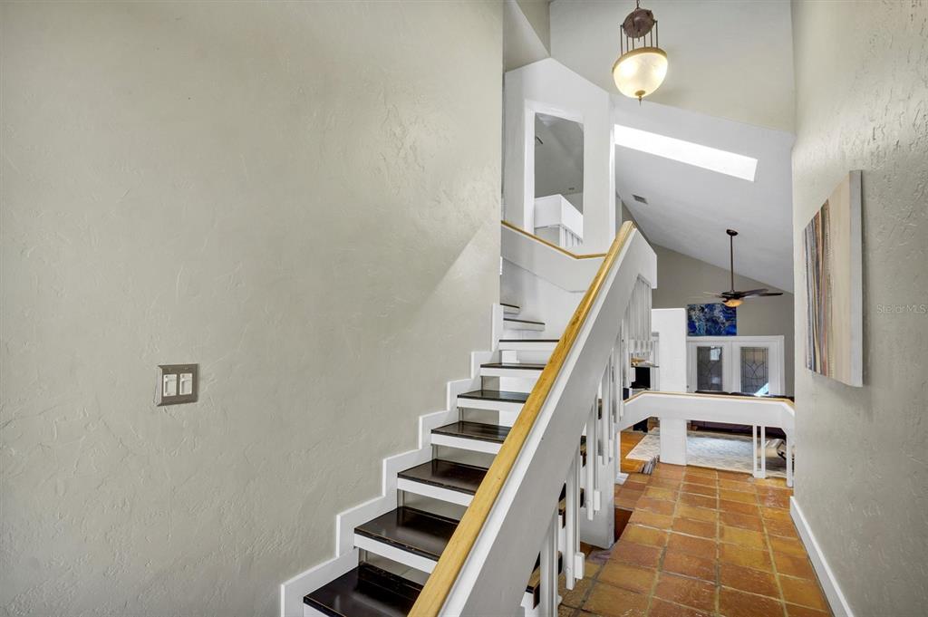A staircase with dark wood treads and white railings leads to an upper level — 21 CASARENA COURT, WINTER HAVEN, FL