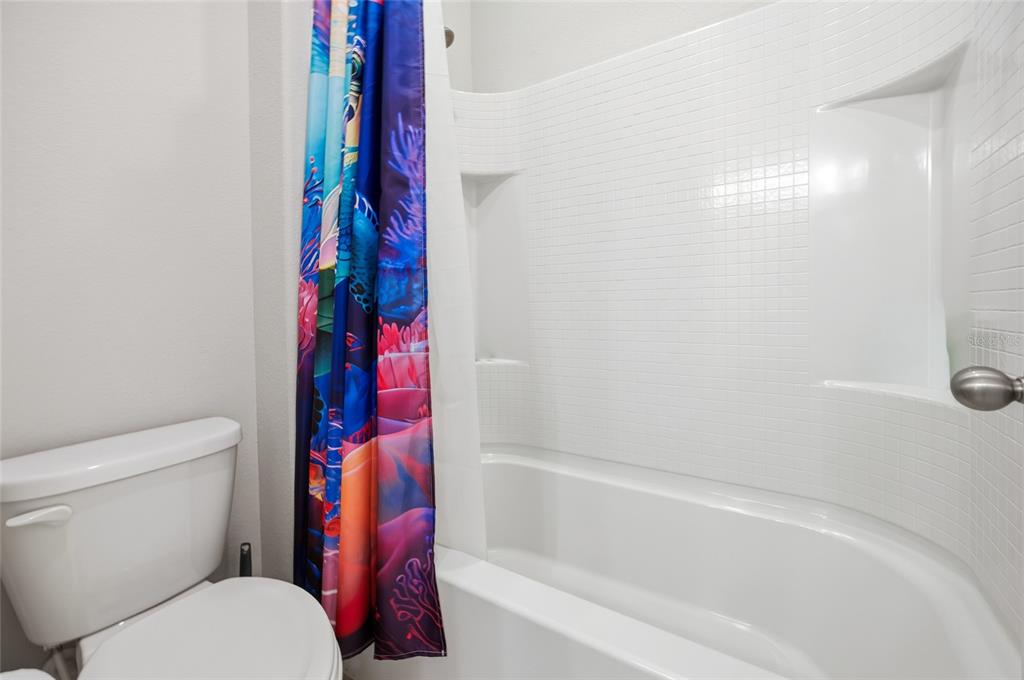 A bathroom features a white bathtub with tiled walls, a shower curtain, and a toilet — 5626 SW 50TH COURT, OCALA, FL
