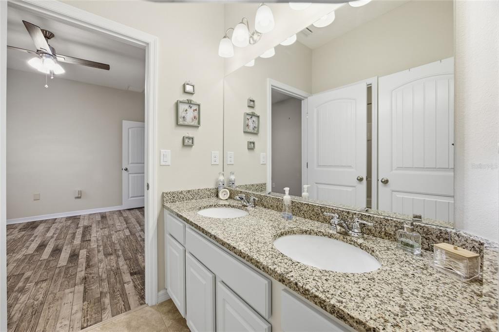 A bathroom features a double-sink granite vanity with white cabinets and a large wall mirror — 5626 SW 50TH COURT, OCALA, FL