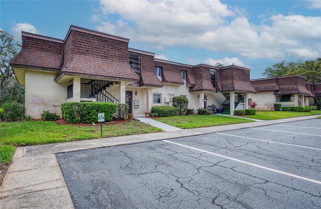 A two-story apartment building with a brown mansard roof and a cracked asphalt parking lot — 7040 COGNAC DRIVE UNIT 3, NEW PORT RICHEY, FL