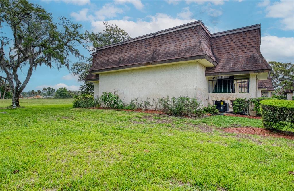 A side view of a two-story building with a mansard roof and a grassy yard — 7040 COGNAC DRIVE UNIT 3, NEW PORT RICHEY, FL