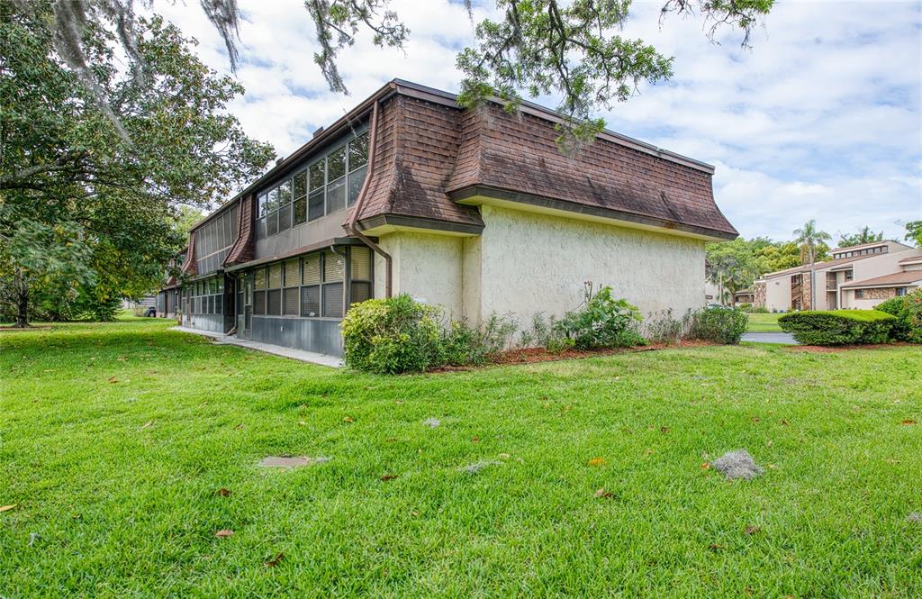 A two-story building with a mansard roof and stucco siding sits on a grassy lawn — 7040 COGNAC DRIVE UNIT 3, NEW PORT RICHEY, FL