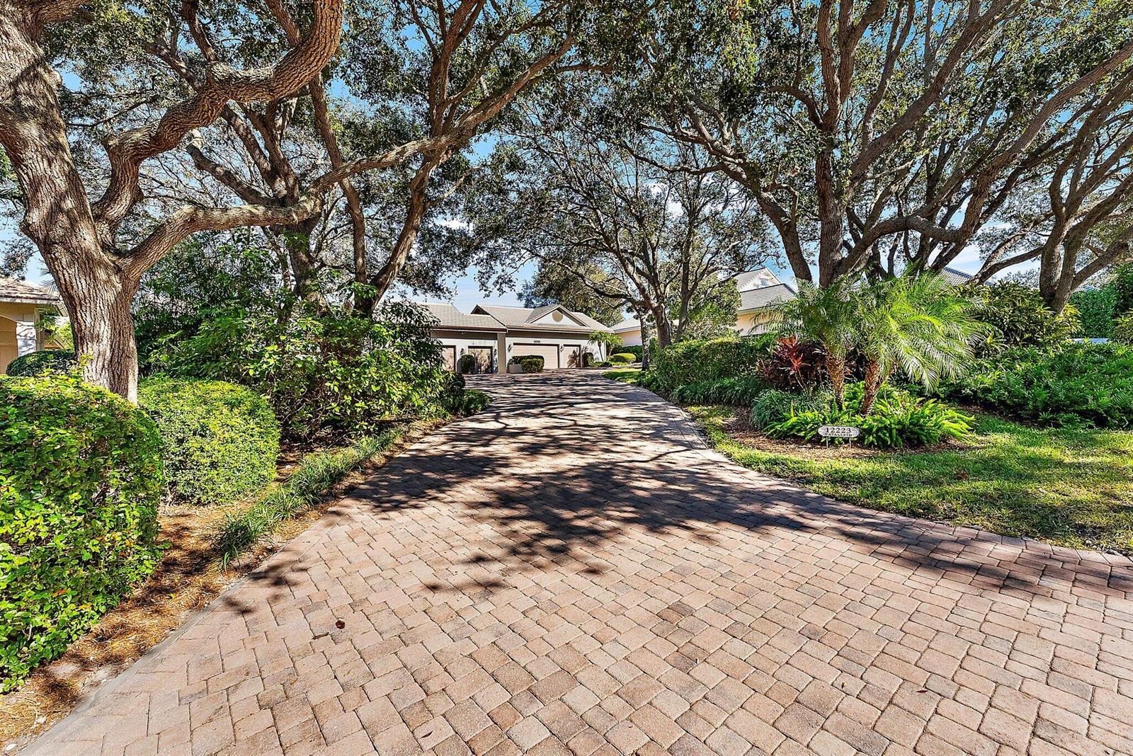 A paved driveway leads toward a house shaded by large, mature oak trees — 12223 SE Birkdale Run, Jupiter FL 33469, JUPITER, FL