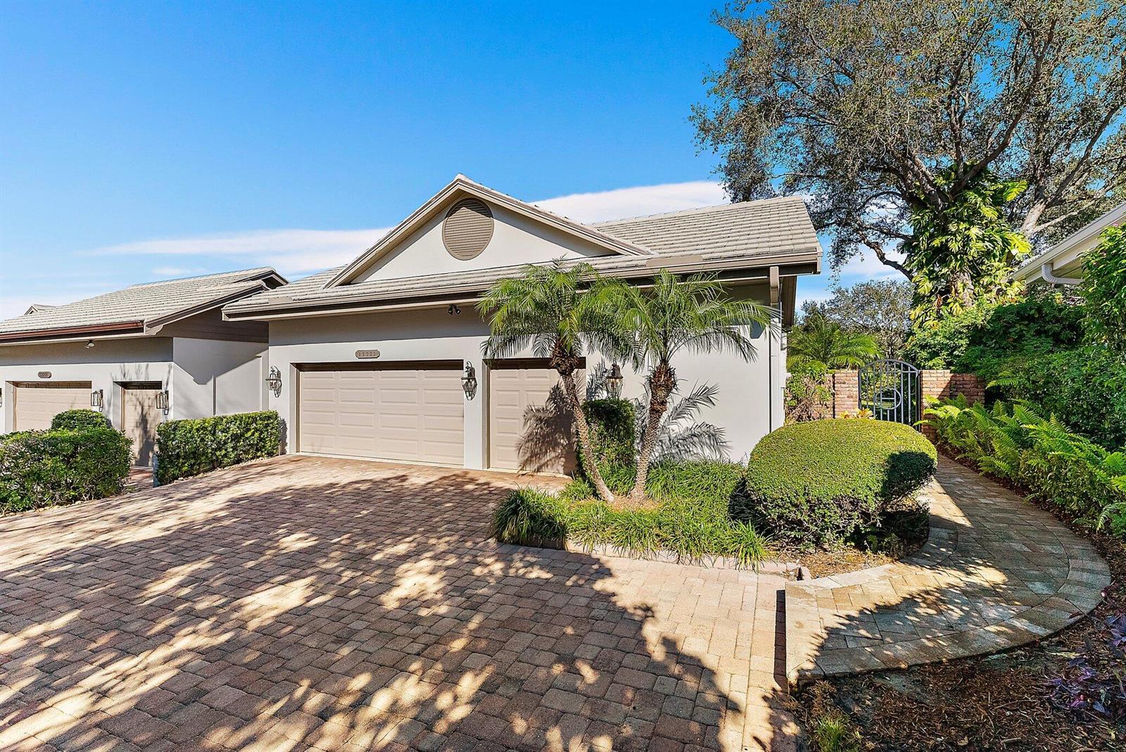 A beige house with a two-car garage and a paved driveway under a clear sky — 12223 SE Birkdale Run, Jupiter FL 33469, JUPITER, FL