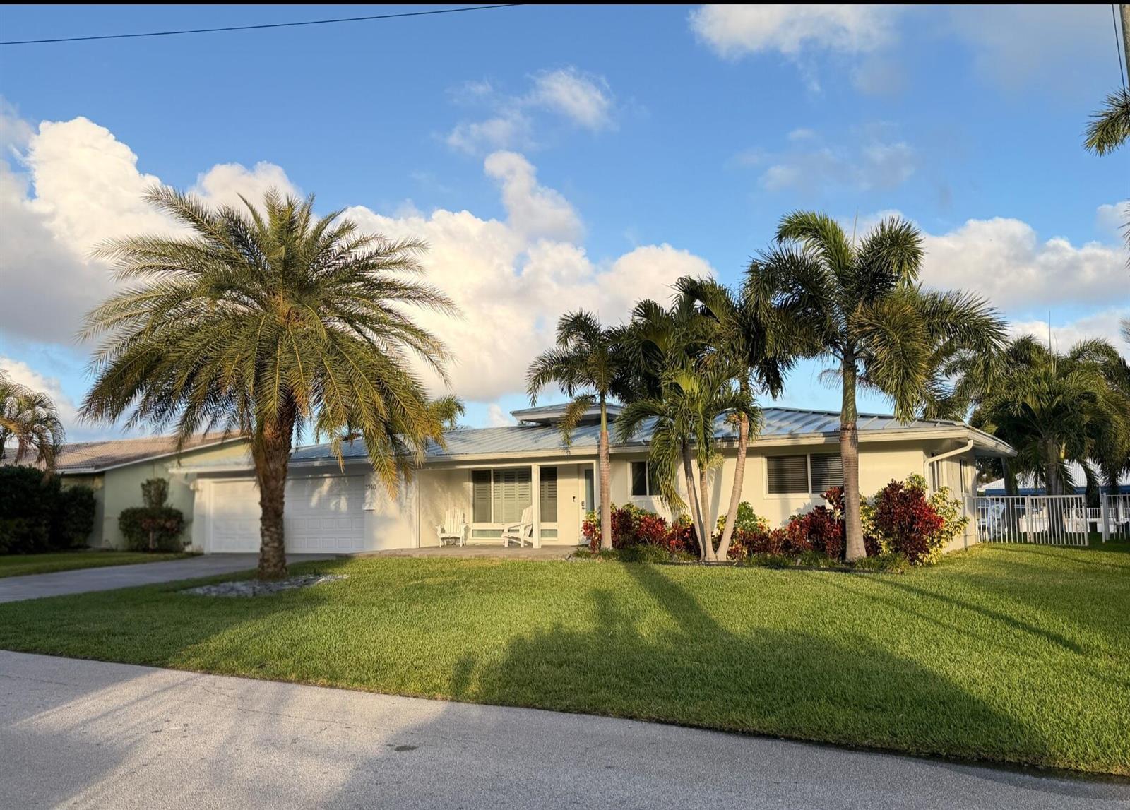 A single-story house with a metal roof, palm trees, and a manicured lawn — 3910 NE 26th Avenue, Lighthouse Point FL 33064, LIGHTHOUSE POINT, FL