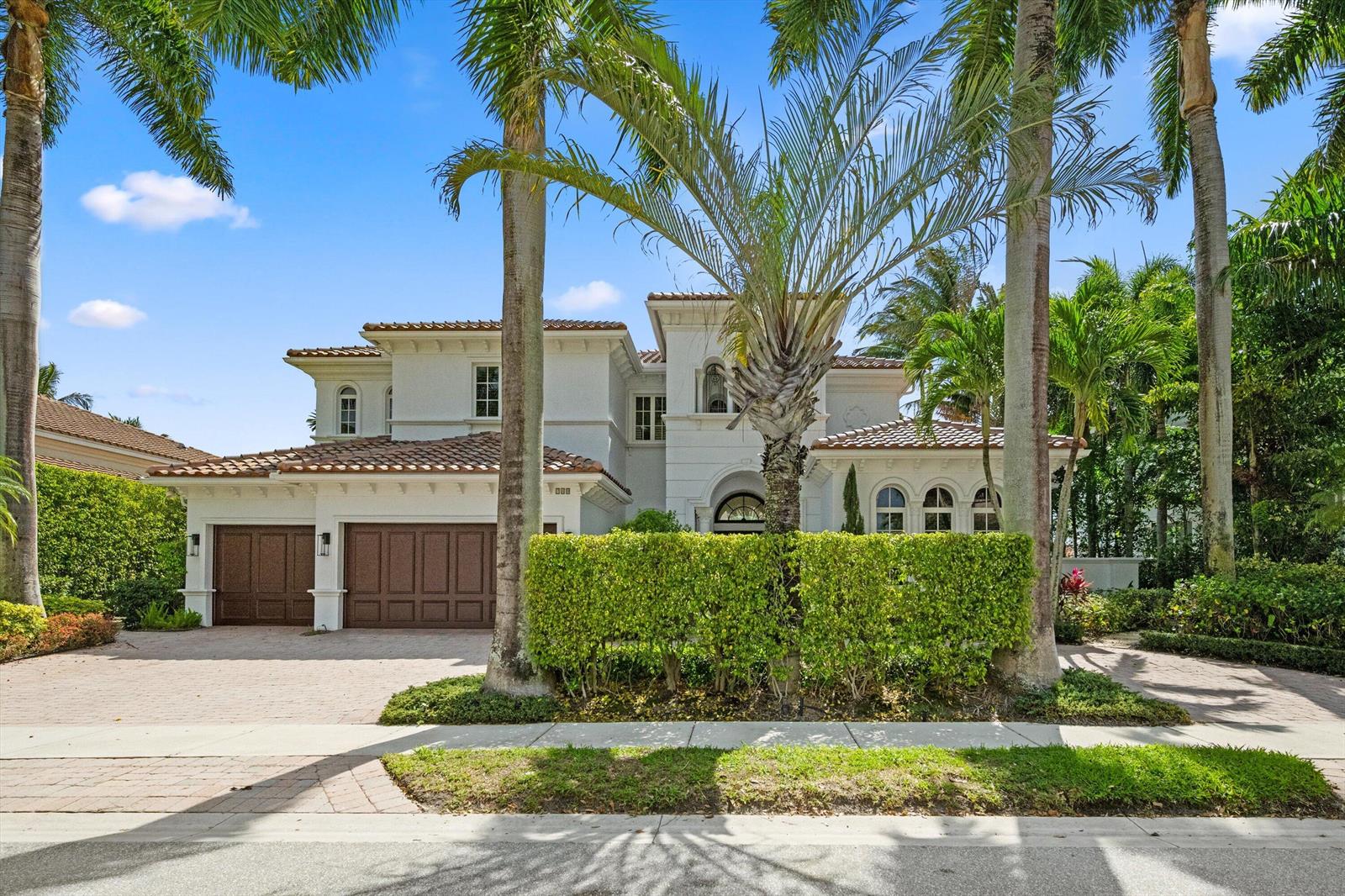 A two-story Mediterranean-style house with a tile roof, brown garage doors, and palm trees — 788 Harbour Isles Place, North Palm Beach FL 33410, NORTH PALM BEACH, FL