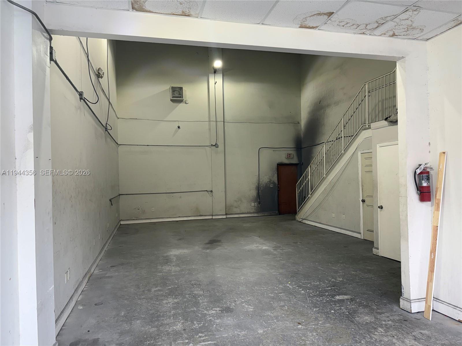 An empty industrial space features concrete floors, high walls, a staircase, and a fire extinguisher — 16723 SW 117th Ave # 6F, Miami FL 33177, MIAMI, FL