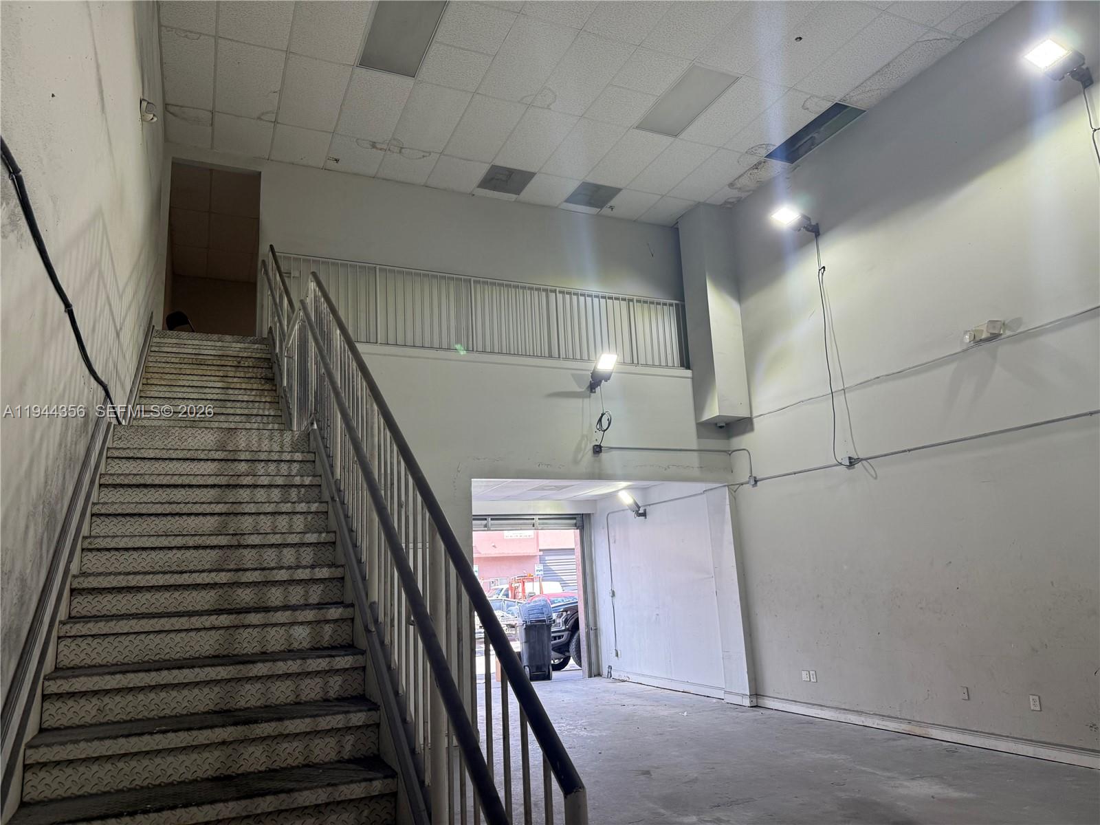 An interior view shows a metal staircase leading to a mezzanine above a warehouse space — 16723 SW 117th Ave # 6F, Miami FL 33177, MIAMI, FL