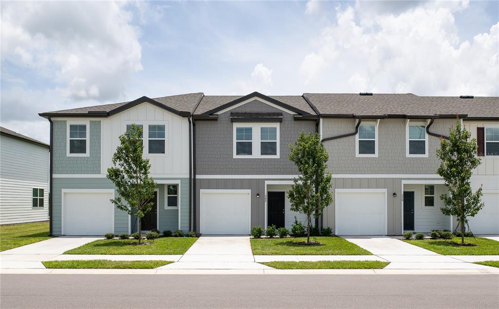 A row of three modern townhouses with attached garages and small front lawns — 3676 SPIRE DRIVE, DAVENPORT, FL