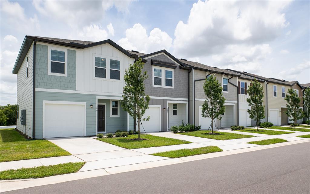 A row of modern townhouses with garages, light-colored siding, and small front lawns — 3676 SPIRE DRIVE, DAVENPORT, FL