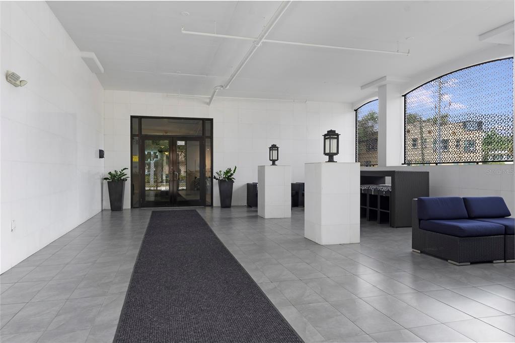 A modern covered entryway features tiled floors, a long runner rug, and outdoor lounge furniture — 226 5TH AVENUE N UNIT M02, ST PETERSBURG, FL