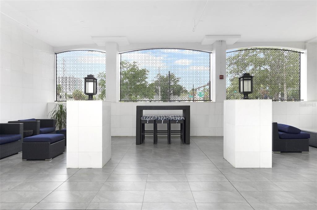 A covered outdoor patio features tiled flooring, wicker furniture, and two white pedestals with lanterns — 226 5TH AVENUE N UNIT M02, ST PETERSBURG, FL