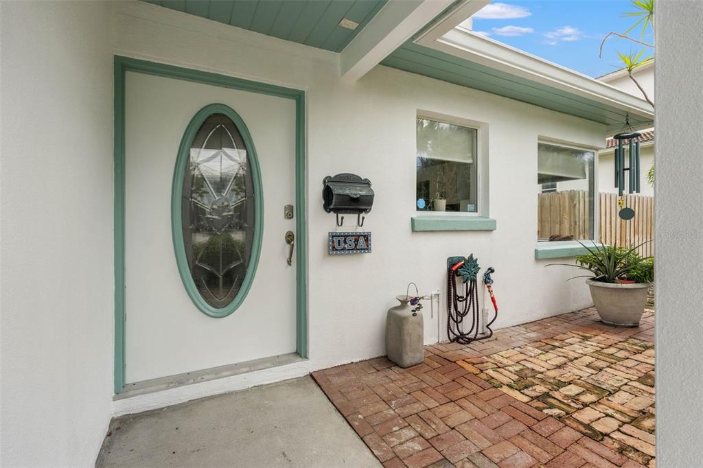 An exterior view of a home entrance with a white door, brick patio, and mailbox — 105 ADALIA AVENUE, TAMPA, FL