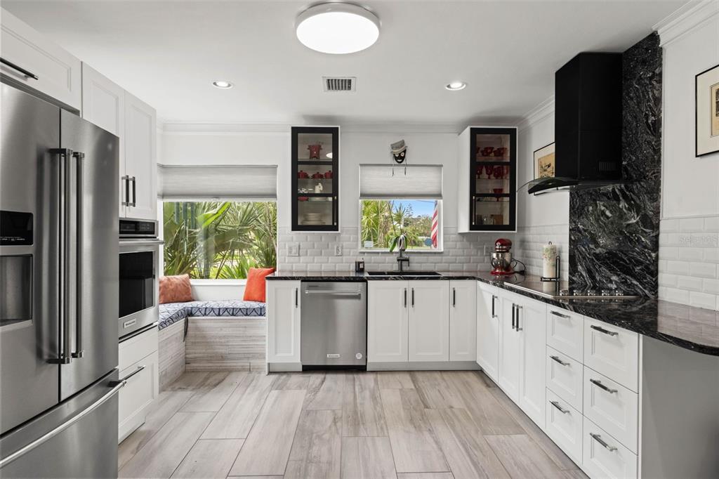 A modern kitchen features white cabinetry, stainless steel appliances, black countertops, and a window seat — 105 ADALIA AVENUE, TAMPA, FL