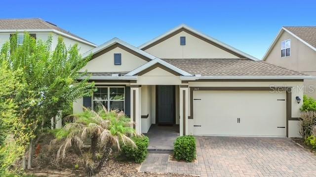 A single-story house with a beige exterior, a two-car garage, and a paved driveway — 2427 ZABALLINA PLACE, DAVENPORT, FL